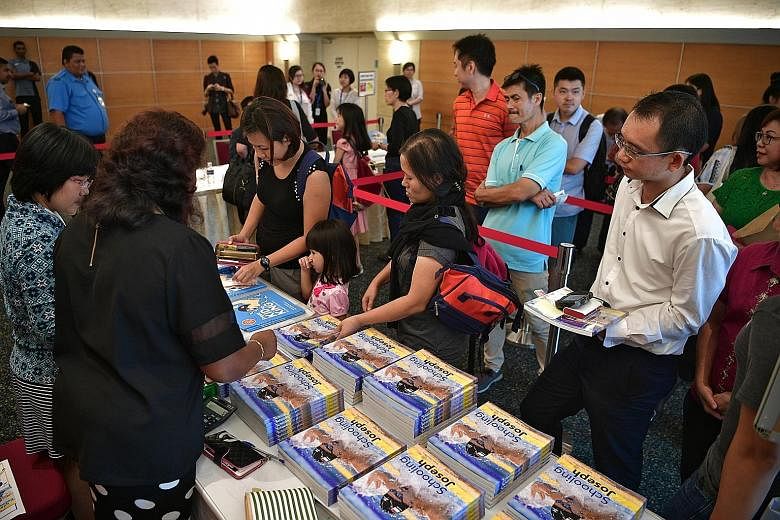 Fans of the swim star queueing to buy two authorised biographies, From Kid To King and Schooling Joseph, at the SPH News Centre yesterday. Olympic champion Joseph Schooling (in red) with ST news editor Marc Lim, who wrote From Kid To King, at the SPH