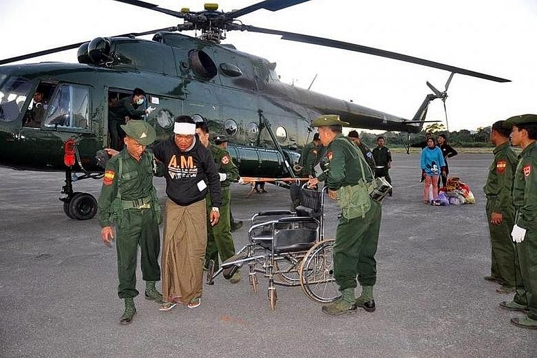 Myanmar soldiers helping an injured man in Shan state on Sunday. Eight people were killed when a coalition of northern rebels attacked military and police outposts on the border on Sunday.