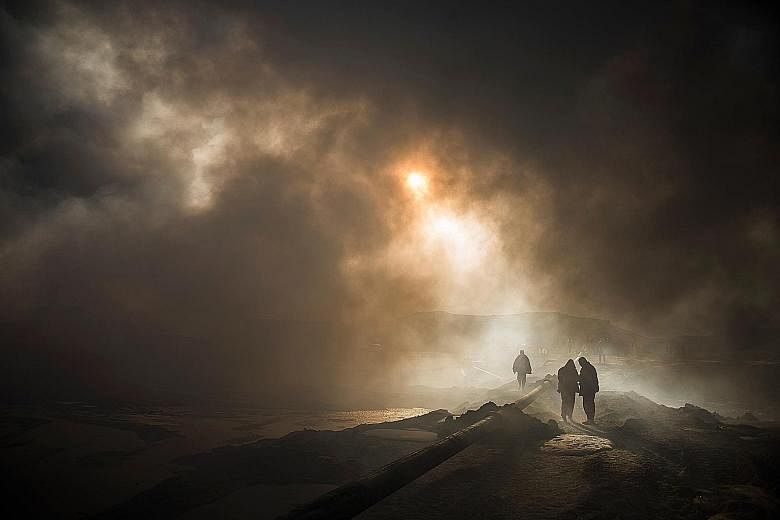 The sun is reduced to a mere glow by dense smoke as firefighters assemble a water pipeline in the town of Qayyarah, some 70km south of Mosul. Engineers, firefighters and policemen have been trying since August to put out fierce fires from oil wells s