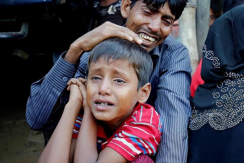 A distraught Rohingya Muslim man and his son after being caught by Border Guard Bangladesh troops while illegally crossing the Myanmar border.
