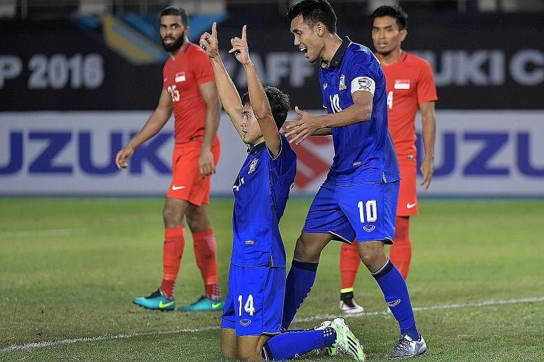 Thailand's Sarawut Masuk (No. 14) celebrating his winning goal with his skipper Teerasil Dangda after leaping the highest to head the game's only goal past Singapore goalkeeper Hassan Sunny.