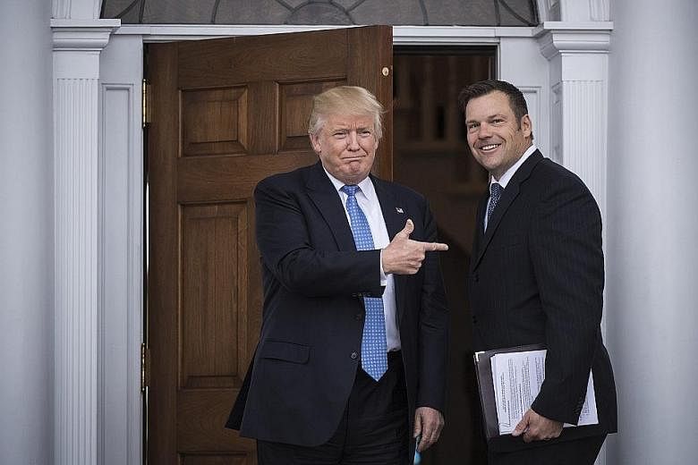 Mr Trump greeting Kansas secretary of state Kris Kobach at the Trump National Golf Club Bedminster in New Jersey on Sunday.