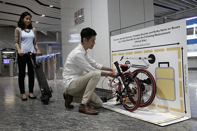 LTA staff yesterday showing a foldable bike and a kick scooter that conform to the dimensions shown on a chart placed at the Little India MRT station. Such signs will be introduced at all MRT and LRT stations and at bus hubs and interchanges.