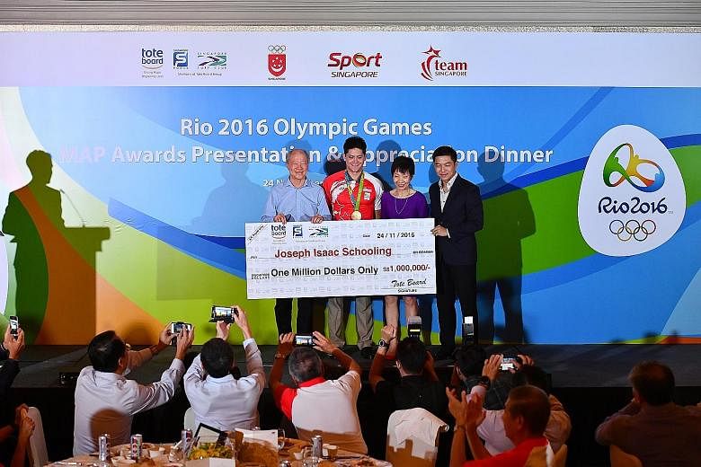 Joseph Schooling (in red) receiving a mock cheque for $1 million last night from Tote Board chairman Moses Lee (left), Minister for Culture, Community and Youth Grace Fu and Minister for Social and Family Development Tan Chuan-Jin, who is also presid