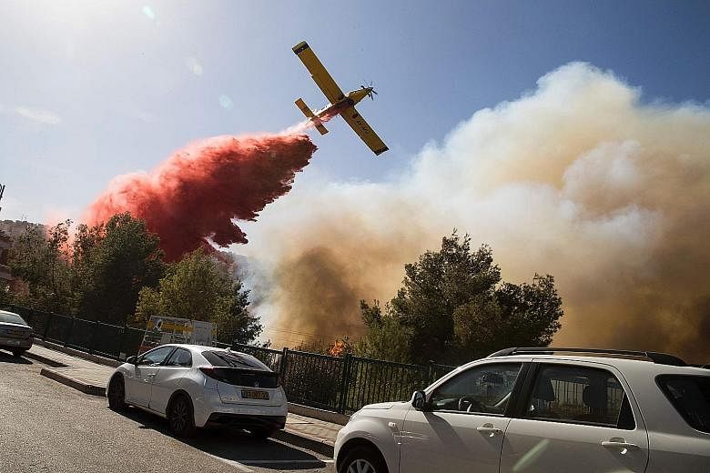 A firefighting plane helping to extinguish a bushfire in the northern Israeli port city of Haifa yesterday. About 50,000 Israelis fled their homes on the outskirts of the country's third city while others were trapped inside as firefighters struggled