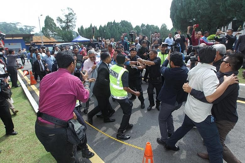 Mr Khalid (wearing a pink shirt and a red tie) being shielded by police and security personnel after he was attacked just outside the Parliament building on Thursday.