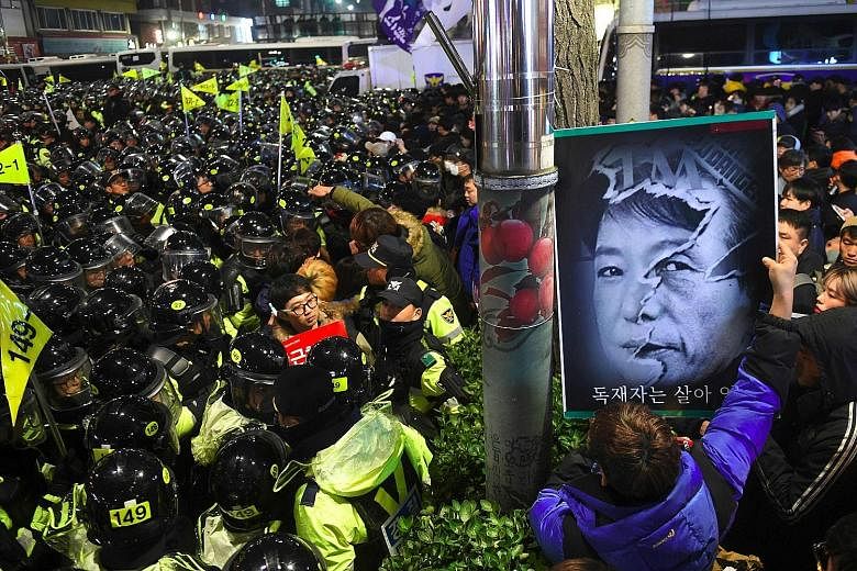 South Korean riot police grappling with protesters marching on the presidential Blue House in Seoul during a rally demanding the resignation of scandal-hit President Park Geun Hye yesterday. Lawmakers are considering a possible move to impeach Ms Par