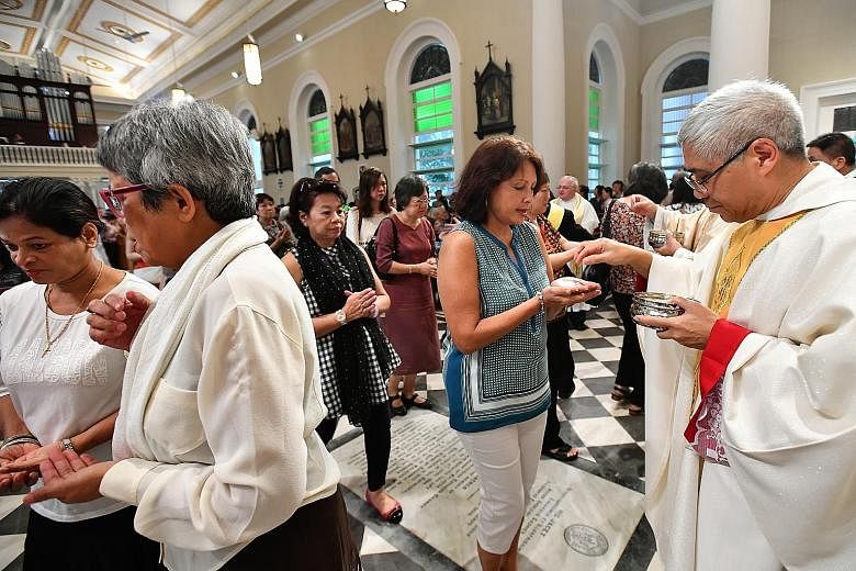 Catholics receiving communion from Archbishop Goh during mass at the newly restored Cathedral of the Good Shepherd last Sunday.
