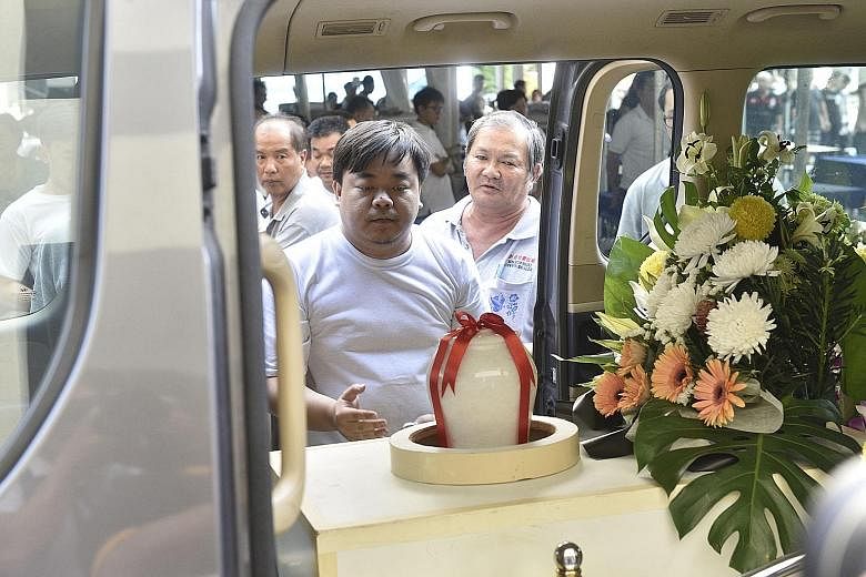 Mr Chee Keong placing the urn containing his father Fong Meng Tuck's ashes in a hearse before his funeral procession in Penang on Friday.