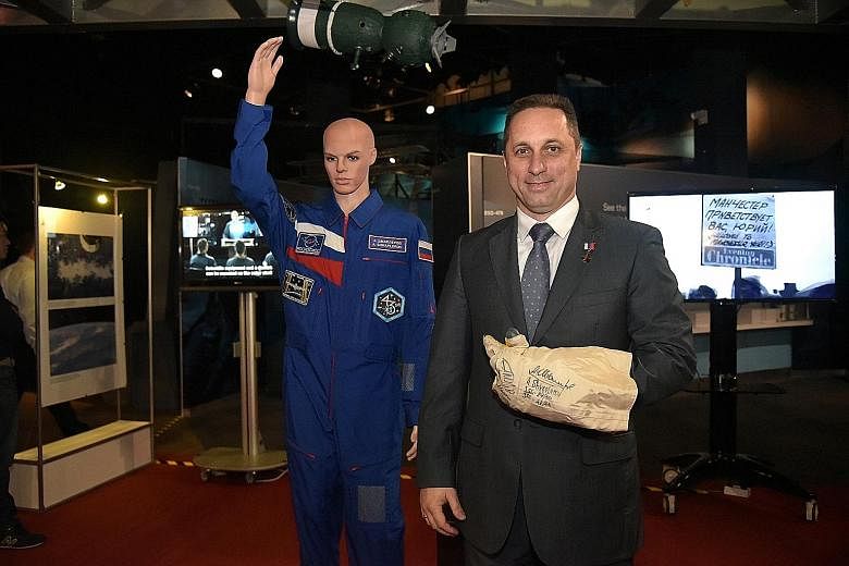 Anton Shkaplerov wearing his space glove and standing next to his inner space suit at the Russian Space Exhibition.