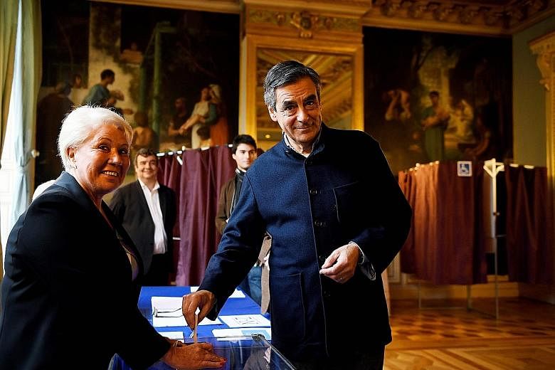 Above: Mr Francois Fillon casting his vote at a polling station in Paris yesterday. Left: Rival Republicans party candidate Alain Juppe leaving a voting booth in Bordeaux after casting his ballot.