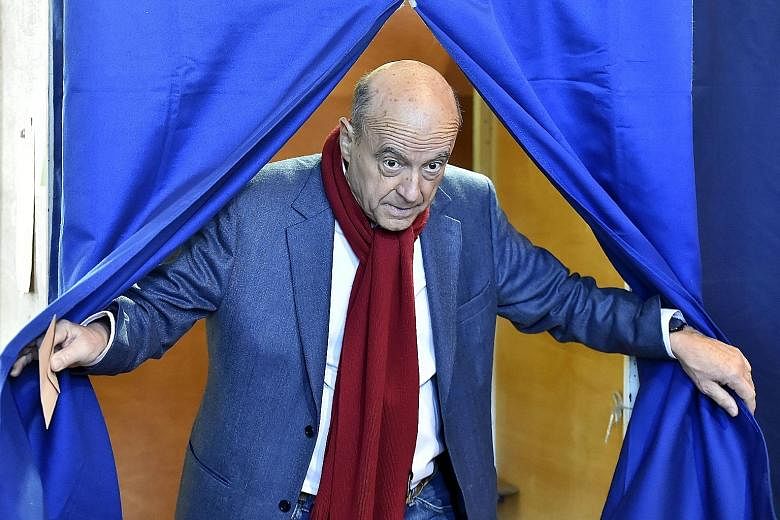 Above: Mr Francois Fillon casting his vote at a polling station in Paris yesterday. Left: Rival Republicans party candidate Alain Juppe leaving a voting booth in Bordeaux after casting his ballot.