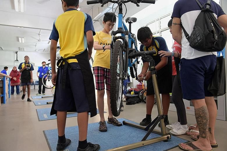Crest Secondary School students demonstrating their bicycle repair skills to potential students and their parents. (From left) Nur Halif Abdullah Sani, Enrique Markus Monteiro and Ryan Ang have benefited from their practice- oriented education at Cre