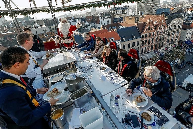 Chefs in safety harnesses serving diners strapped to chairs and suspended on an open platform 35m from the ground - during the Santa In The Sky event as part of Christmas festivities in Brussels on Friday.