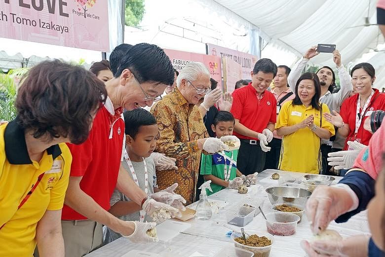 President Tony Tan Keng Yam making rice balls for beneficiaries of the new Project We Care Enrich at the Istana yesterday. With him were People's Association (PA) chief executive director Ang Hak Seng (second from left); Minister in the Prime Ministe