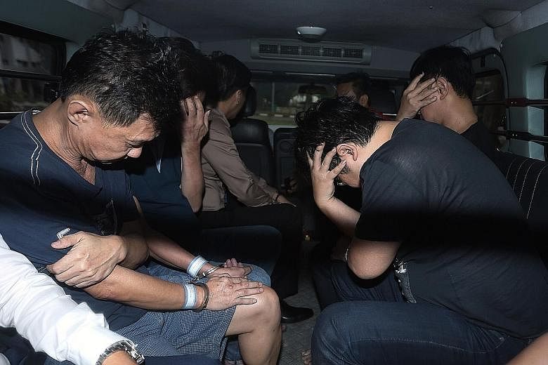 Four of the 11 suspects charged with offences under the Remote Gambling Act and Common Gaming Houses Act on their way to the court in a police van yesterday. They and 22 others were arrested on Sunday after one of the largest operations against a cri