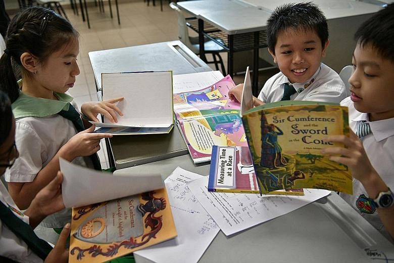 Primary 4 pupils (from left) Vasudevan Suresh Megna (partially hidden), Ellyse Wong, Tan Hai Yang and Bryan Pak with some of the storybooks used in their maths lessons at Woodgrove Primary School, which piloted the literature-based approach in 2014. 