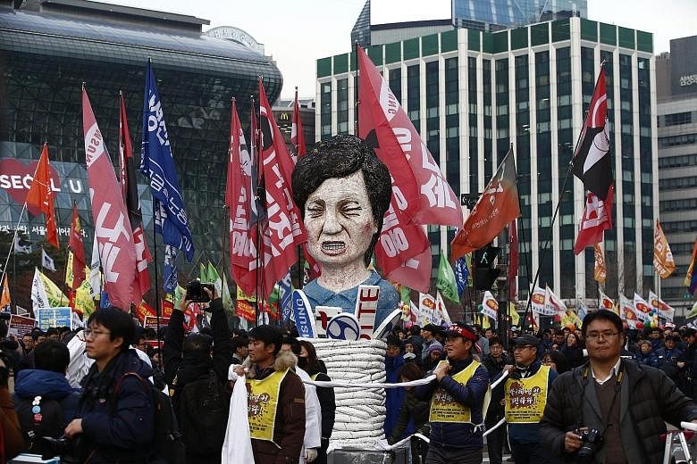 Protesters from the Korean Confederation of Trade carrying an effigy of President Park Geun Hye during a march against her in front of the City Hall in Seoul yesterday.
