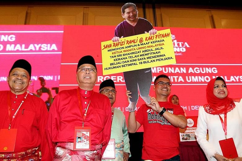 Umno division chief Jamal Yunos holding up a cutout of opposition MP Rafizi Ramli at Umno's annual assembly yesterday, to loud applause from the attending delegates. The poster says that Rafizi is seeking forgiveness from Umno Women chief Shahrizat A
