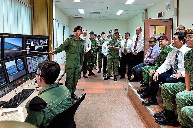 Crown Prince Al-Muhtadee Billah (wearing red beret) observing a firing demonstration on a simulator with (seated in front row, from right) Major-General Melvyn Ong, Mr Ong Ye Kung and Dr Janil Puthucheary.
