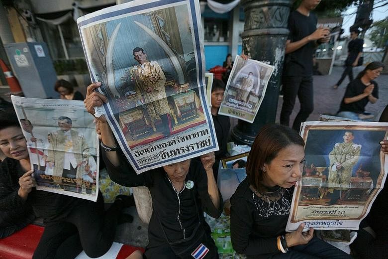 Thai well-wishers holding up portraits of Thai Crown Prince Maha Vajiralongkorn on the front page of newspapers as they gathered outside the Grand Palace in Bangkok yesterday. The 64-year-old Crown Prince became Thailand's new king yesterday after in