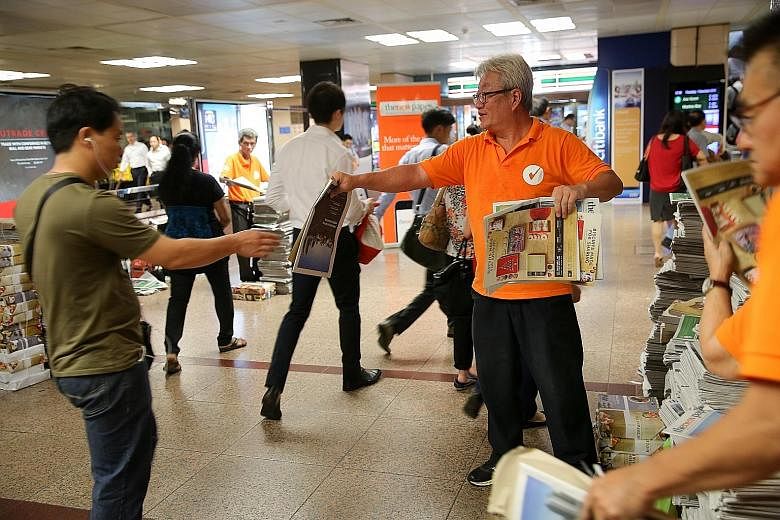 Above: Readers waiting to get their goodie bags, which include Owl coffee sachets and vouchers, after collecting their copies of TNP at Raffles Place yesterday. Left: A commuter grabbing a TNP copy at Raffles Place MRT station, one of the regular poi