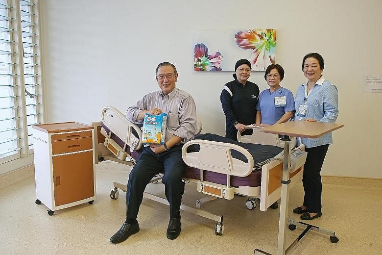 Mr Ee holding the Confidence diapers Home Care Enterprises is launching next month. He is seated on HCE's first product - an electric homecare bed. With him are (from far left) Ms Zahara, CGH senior nurse manager Fong Poh Chee and HCE coordinator Iri