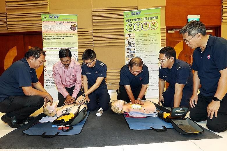 Singapore Civil Defence Force Third Sergeant Daniel Yuen (third from left) and Private Alif Irwan (fifth from left) instructing bus drivers how to perform cardiopulmonary resuscitation at yesterday's seminar.