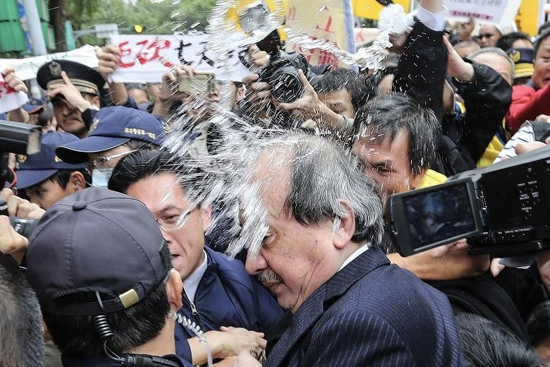 A protest outside Taiwan's Parliament descended into chaos yesterday as workers angry over a proposed cut to public holidays attacked a lawmaker and threw smoke bombs. Senior Democratic Progressive Party official Ker Chien-ming was shoved, punched an
