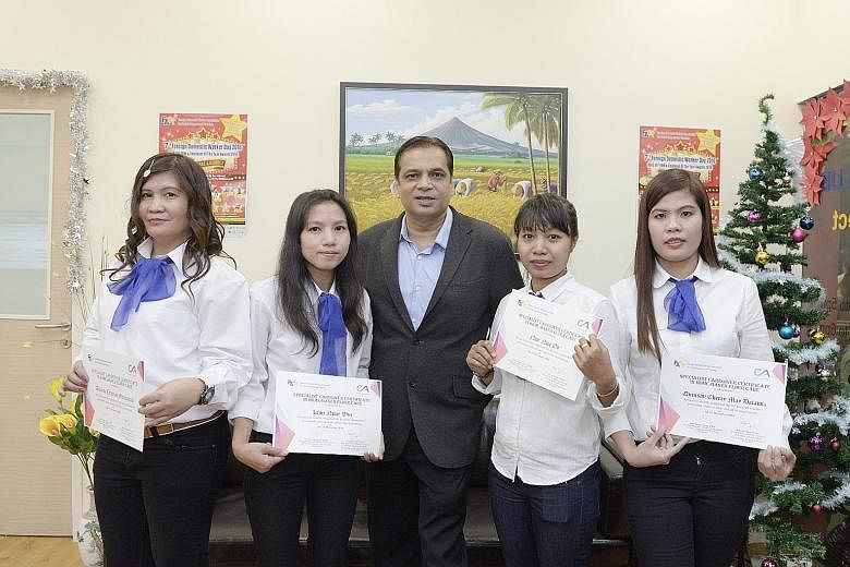 (From far left) Scholarship recipients Cristina Ganancial Alvarez; Khin Nilar Win, 29; Nwe Nwe Oo, 31; and Quinsay Cherry May Dalawis, 33, with Mr Satyaprakash Tiwari, managing director of the Care Academy, at yesterday's graduation event.