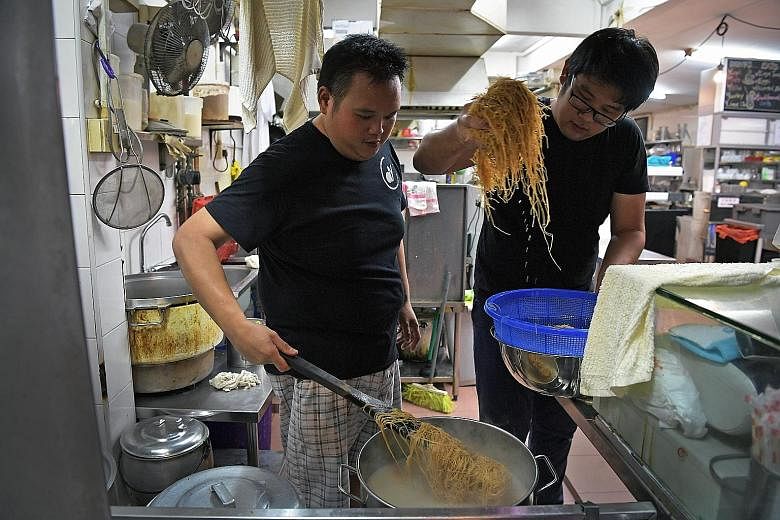 Mr Wong (left) and volunteer Lee Shi Hao, 26, preparing oyster mee suah for the elderly last month at 73@Hillcrest, a coffee shop by day and bistro by night.