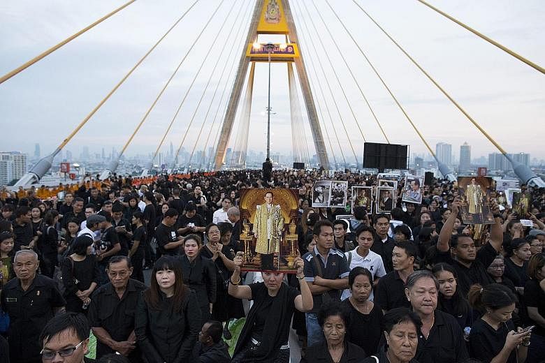 Thousands of Thais gathered on a Bangkok bridge named after the late King Bhumibol Adulyadej on what would have been his birthday yesterday, the latest organised mass display of grief in a nation adjusting to life without him. For much of his seven-d