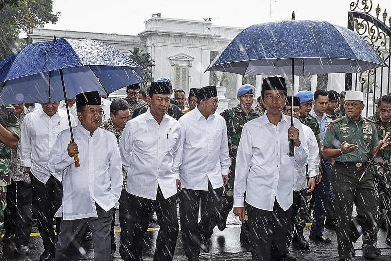 President Joko (right, with umbrella) and Vice-President Kalla (far left) walking out from the Merdeka Palace to meet protesters at a rally against Governor Basuki in Jakarta last Friday. Mr Joko went despite being told by Indonesian intelligence tha