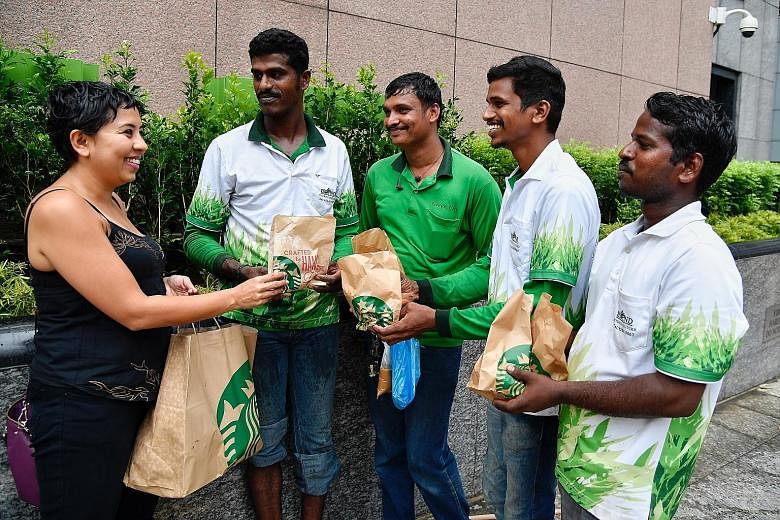 Ms Dipa Swaminathan distributing some of the food items from Starbucks outlets to foreign workers (from left) Satish Kumar, 30; Sundara Murthy, 26; Vijay Kumar, 30; and Ganeshan Siva Kumar, 29.