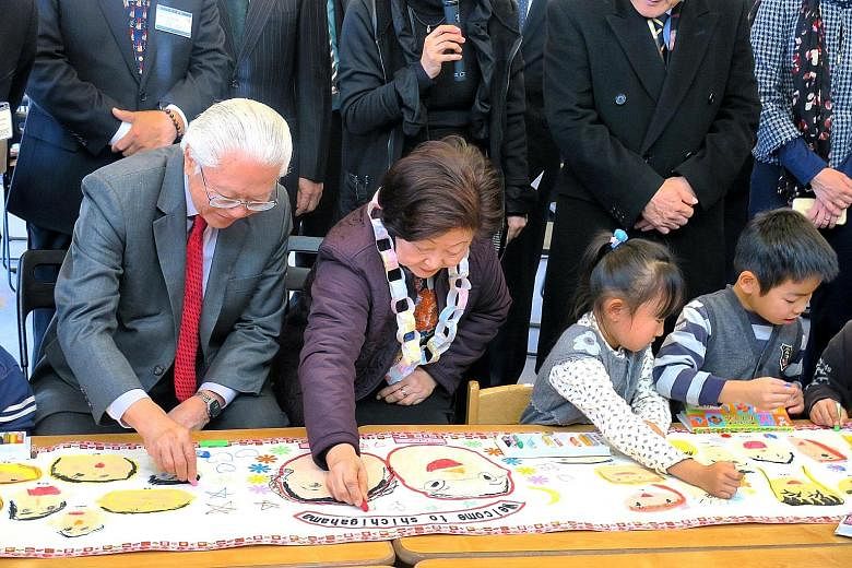 Pupils of Shichigahama Toyama Nursery School, together with Dr Tan and Mrs Tan, adding the finishing touches to a banner artwork featuring drawings of the children and the Singapore President and his wife.