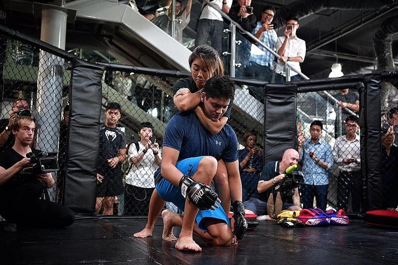 Angela Lee, One Championship's first female world champion, shows Singapore's Olympic swimming gold medallist Joseph Schooling how to execute a choke hold at Evolve MMA gym at Far East Square.