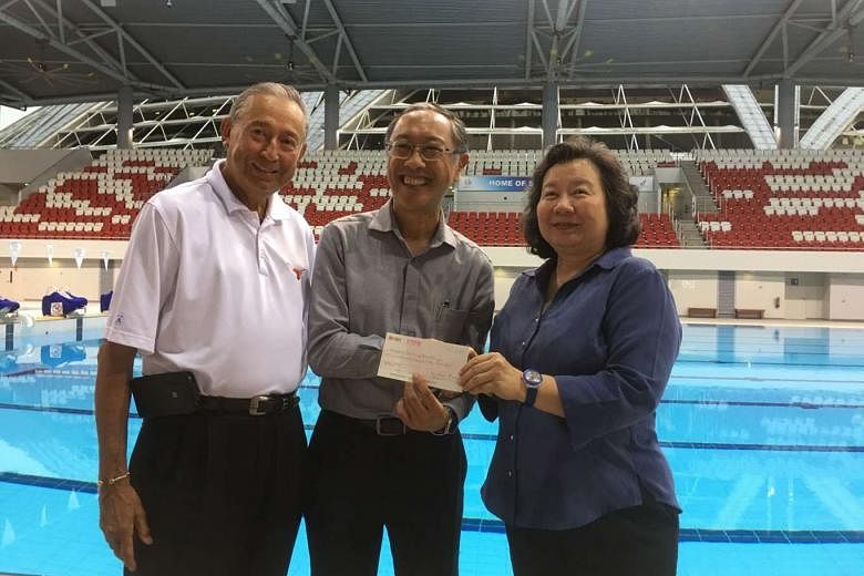 SSA president Lee Kok Choy (centre) receives a $200,000 cheque from May and Colin Schooling. The amount is 20 per cent of the money Joseph Schooling received from SNOC's awards programme.