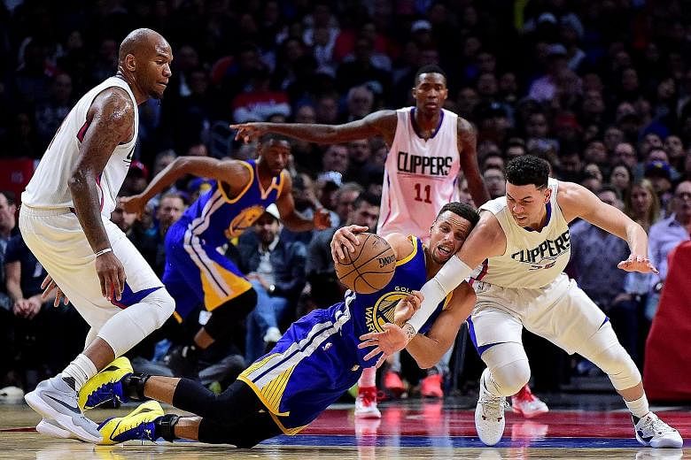 Golden State Warriors guard Stephen Curry falls but keeps the ball from the Los Angeles Clippers guard Austin Rivers during his team's 115-98 National Basketball Association victory at the Staples Centre. He finished with three turnovers but tied a c