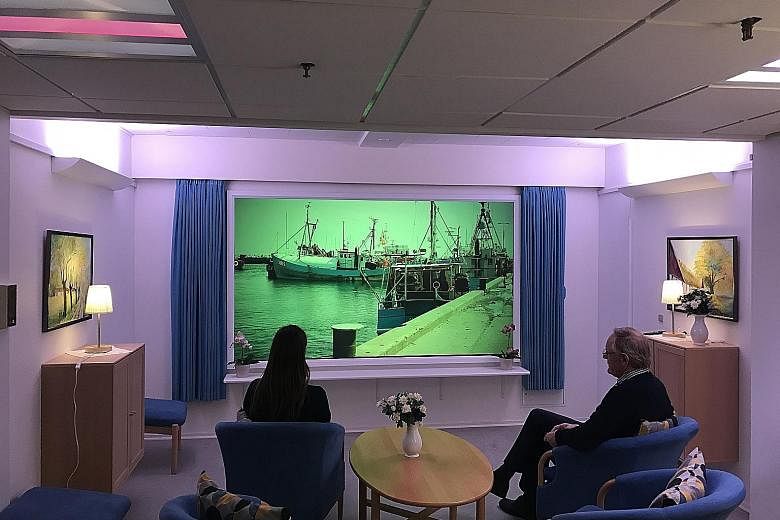 A room for dementia patients at Lindehaven Care Centre in Copenhagen, which uses different lighting to regulate the body's natural circadian rhythm. Images relevant to a patient's past, such as a familiar place, are also shown on a screen as a form o