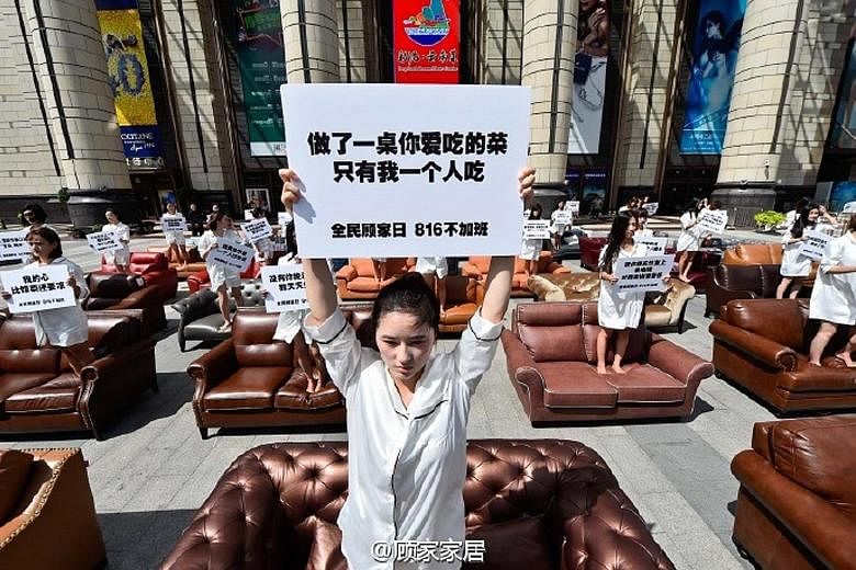 A woman in Shanghai protesting against the impact of overtime work on families. The placard she is holding reads: "Prepared a feast, but I'm the only one eating the food."