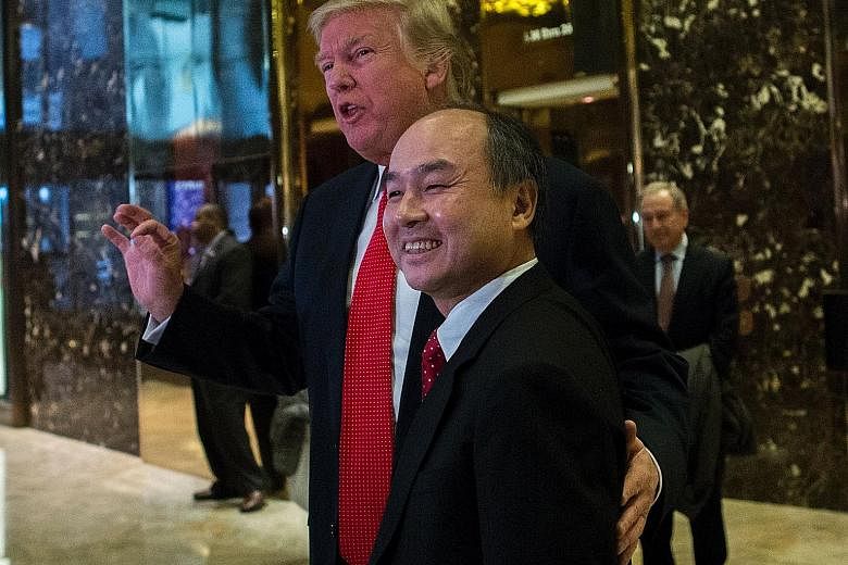 US President-elect Trump with SoftBank founder and chief executive Son in the lobby of Trump Tower last Tuesday. Mr Son pledged to create 50,000 jobs and invest US$50 billion in US start-ups, and has a 300-year plan for his US$68 billion tech giant.