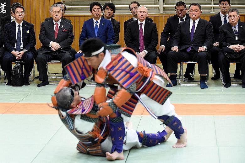 Mr Abe (third from left), flanked by Mr Putin and former premier Yoshiro Mori, at a judo demonstration at the Kodokan Judo Institute in Tokyo yesterday. Japan and Russia have agreed to set up a joint fund that will invest in sectors such as energy, u