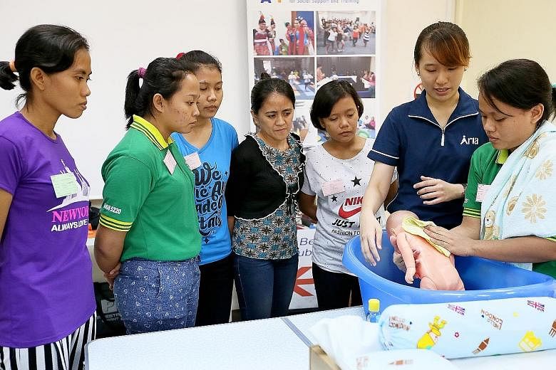 Ms Salmon Law (second from right), 22, from Aria Training and Consultancy teaching trainees infant care skills earlier this month. The Foreign Domestic Worker Association for Social Support and Training has launched in-depth courses for maids with tr