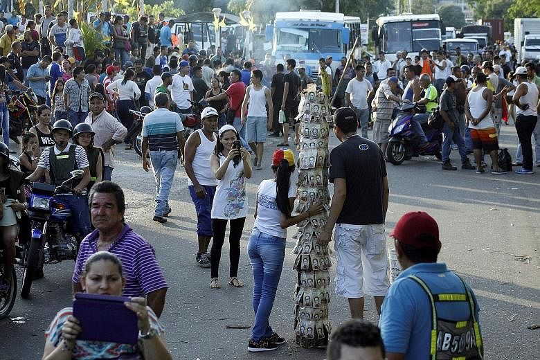 People taking pictures next to a pole covered with 100-bolivar bills during a protest in El Pinal, Venezuela, last Friday. The 100-bolivar note ceased to be legal tender last Thursday and Venezuelans were to have 10 days after that to exchange them a