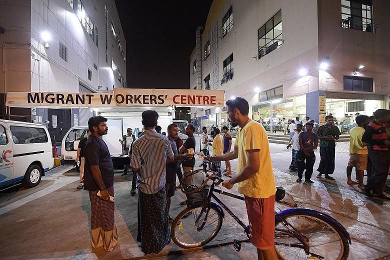 Mr Raja Ramasamy Raj (third from left), 39, and Mr Jeyabal Simeon (left), 32, both volunteers with the Migrant Workers' Centre, talking to migrant workers in Tuas View Square. The centre has conducted outreach to more than 650,000 foreign workers sin