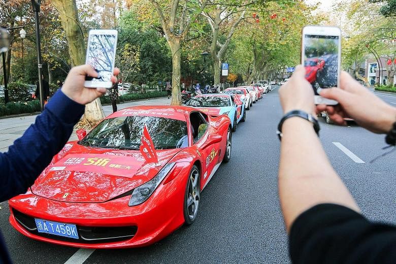 Passers-by taking photos of a Ferrari and other luxury cars covered with advertising banners on a street in Hangzhou, in China's eastern Zhejiang province, recently. The Beijing authorities are as much in a race to tighten capital controls as are Chi