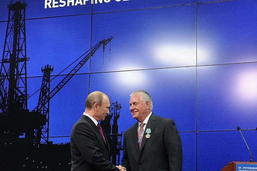 Above: Russia's President Putin (left) with Mr Tillerson at a June 2013 ceremony in St Petersburg to present awards to the heads and employees of major energy companies. Top: Mr Trump (centre), with his daughter Ivanka and Mr Friedman after their 201