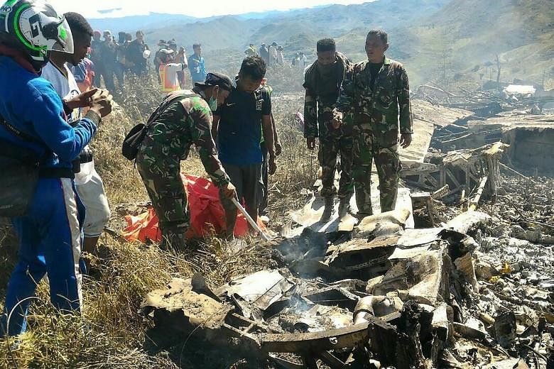 Indonesian military personnel examining the wreckage of an air force plane that crashed in Papua province during a training exercise.