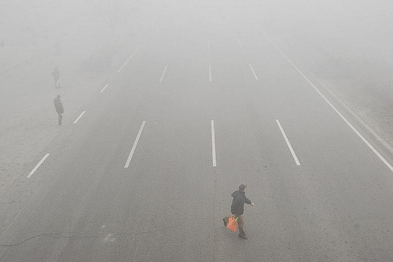 The scene in Liaocheng, Shandong province, yesterday. At least 23 cities in China have issued red alerts on air pollution since Friday. The Forbidden City in Beijing yesterday. PM2.5 levels were around 200, according to data by the US Embassy. A road