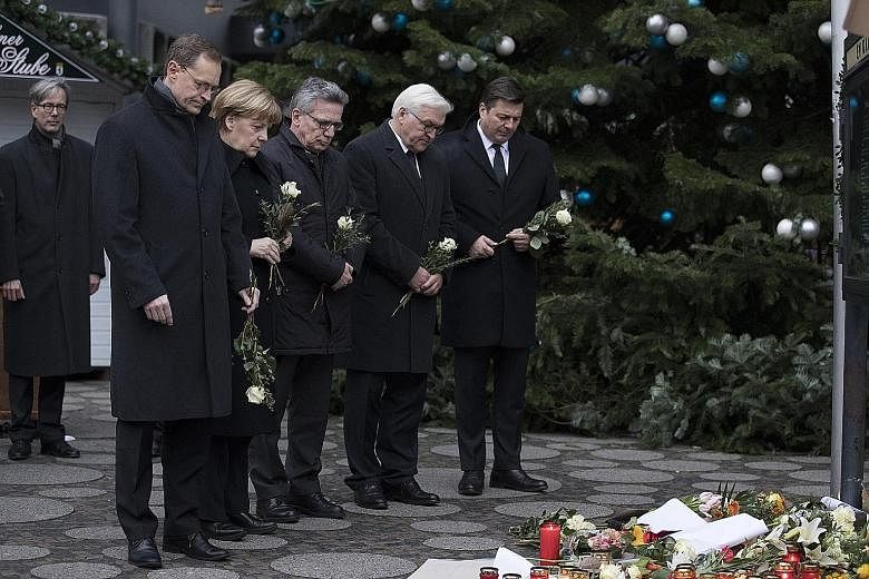 German Chancellor Angela Merkel on Tuesday looking at floral tributes near the scene of Monday's attack in Berlin. With her are (from left) Berlin Mayor Michael Mueller, German Interior Minister Thomas de Maiziere, German Foreign Minister Frank-Walte
